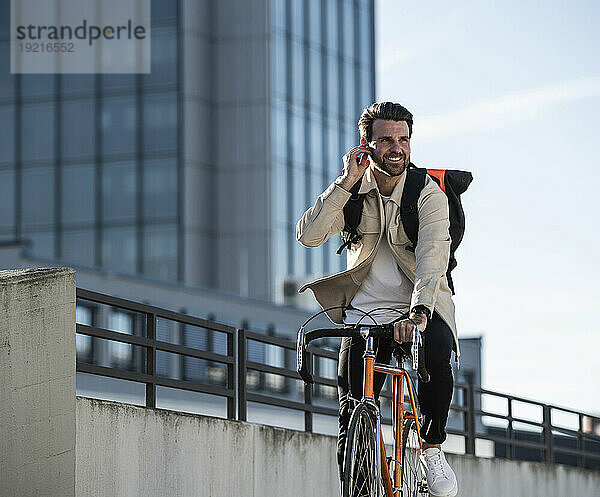 Mann fährt Fahrrad vor Gebäude