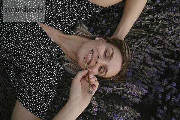 Woman with eyes closed lying on lavender flowers