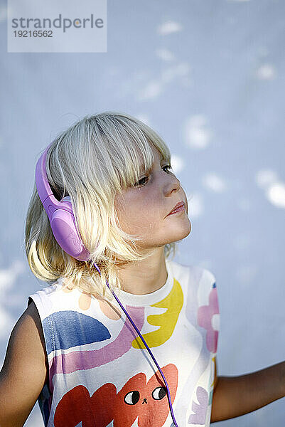Blond girl wearing headphones and listening to music