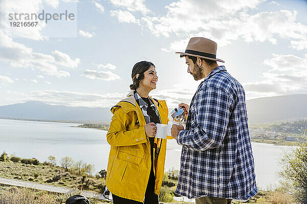 Glückliche Frau schaut Mann an  der Kaffee am See serviert