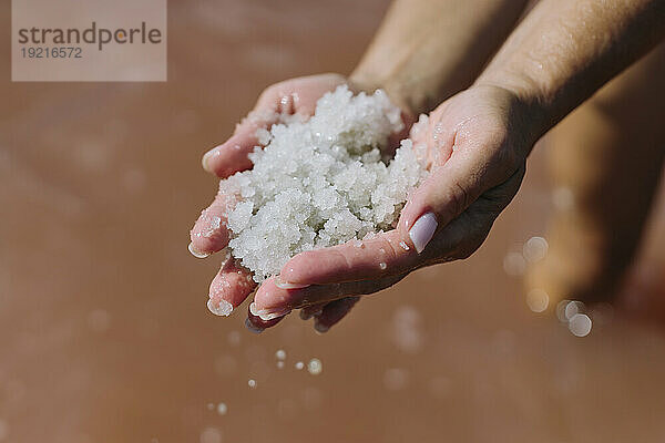 Hands of woman holding salt over lake water