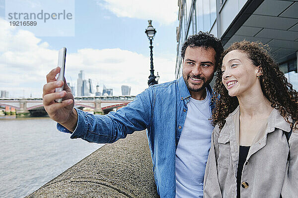 Glücklicher Mann macht Selfie mit Frau per Smartphone