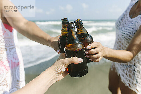 Freunde rösten Bierflaschen am Strand