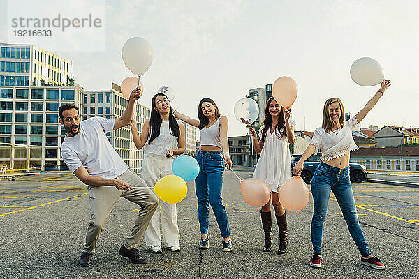 Fröhliche Freunde halten Luftballons auf der Straße