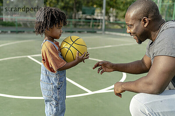 Lächelnder Vater spricht mit Sohn auf dem Basketballplatz