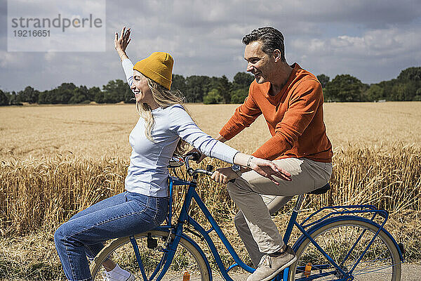 Fröhliche Männer und Frauen genießen die Radtour vor dem Feld