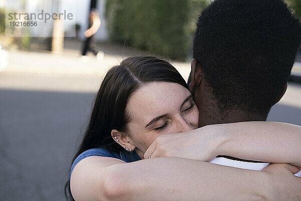 Junge Frau umarmt Mann auf der Straße