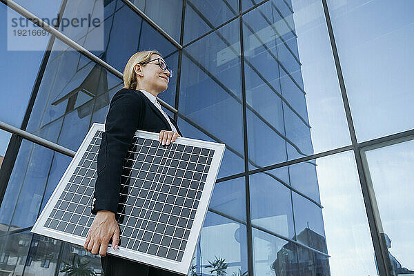 Geschäftsfrau mit Solarpanel am Glasgebäude im Business Center