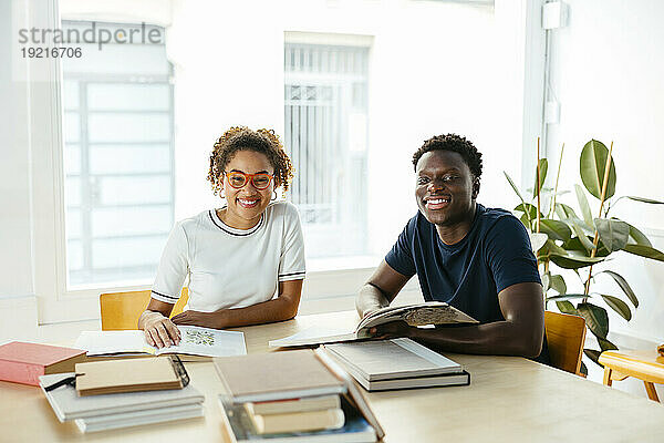 Happy students with books studying in library