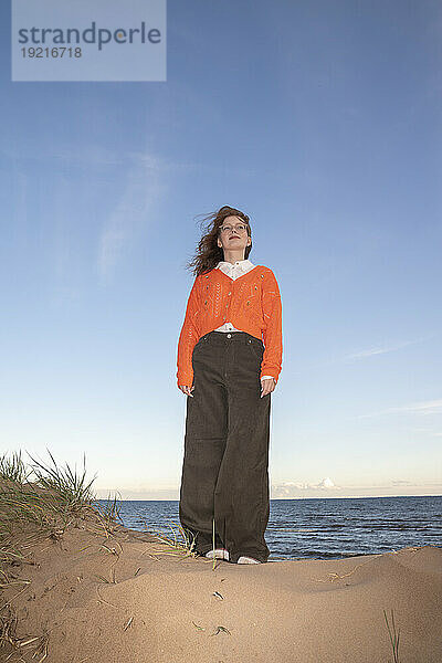 Frau steht auf Sand unter Himmel am Strand