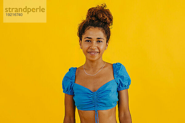 Lächelnde junge Frau vor gelbem Hintergrund