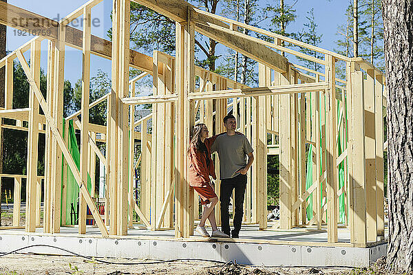 Paar steht an einem sonnigen Tag am Holzkonstruktionsrahmen
