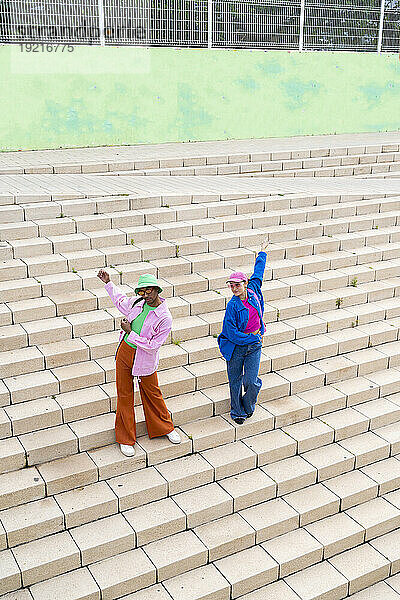 Nicht-binäre Person tanzt mit Frau auf der Treppe