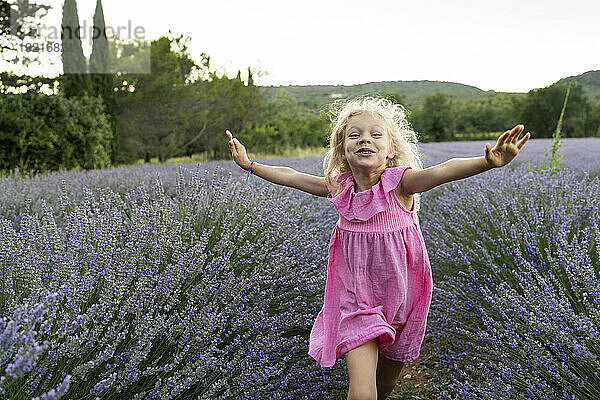 Glückliches Mädchen mit ausgestreckten Armen  das im Lavendelfeld rennt