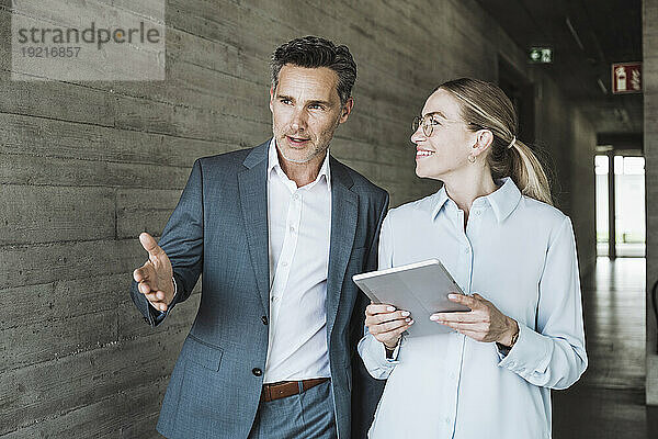 Lächelnde Geschäftsfrau und Geschäftsmann diskutieren gemeinsam im Büro