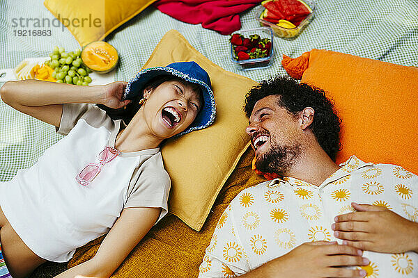 Happy friends enjoying together and lying on picnic blanket