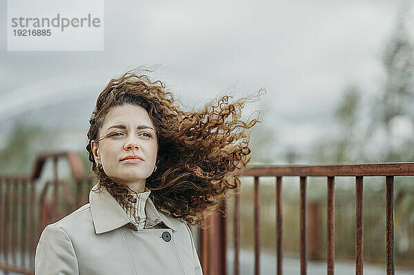 Beautiful woman with curly hair near railing
