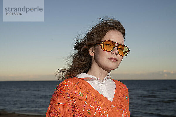 Junge Frau mit Sonnenbrille vor dem Meer