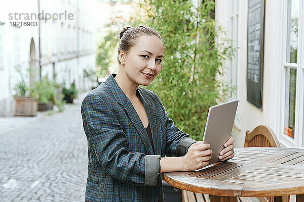 Lächelnde Frau mit Tablet-PC im Straßencafé