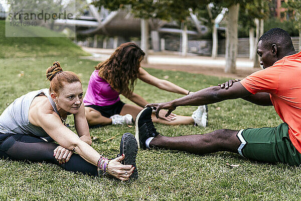 Multiethnische Freunde dehnen und machen Yoga im Park