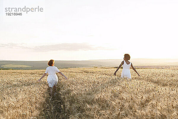 Junge Frau mit Freundin geht im Weizenfeld spazieren