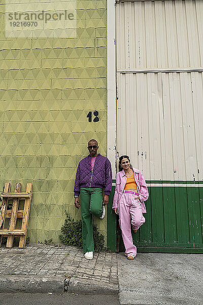 Modisches Paar lehnt gemeinsam an der Wand am Fußweg