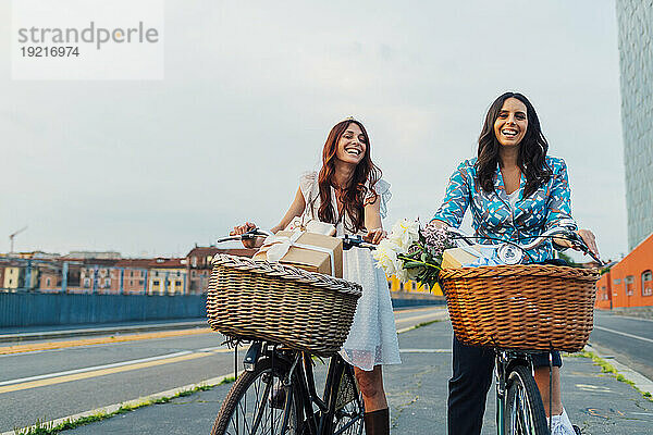 Fröhliche Freunde  die bei Sonnenuntergang gemeinsam Fahrrad auf der Straße fahren