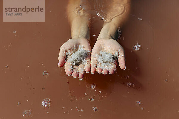 Hände einer Frau  die Salz im See hält