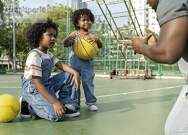 Father explaining to children on basketball court