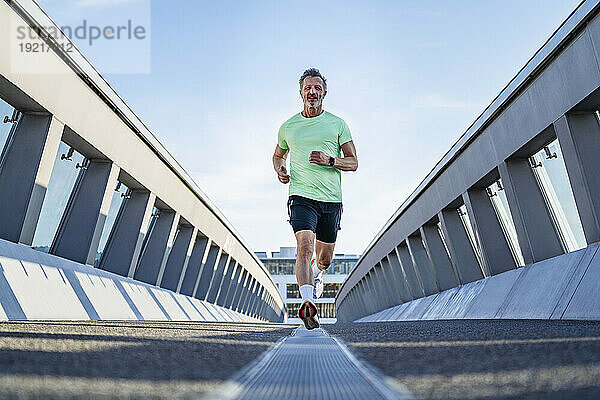 Reifer Athlet joggt auf Fußgängerbrücke