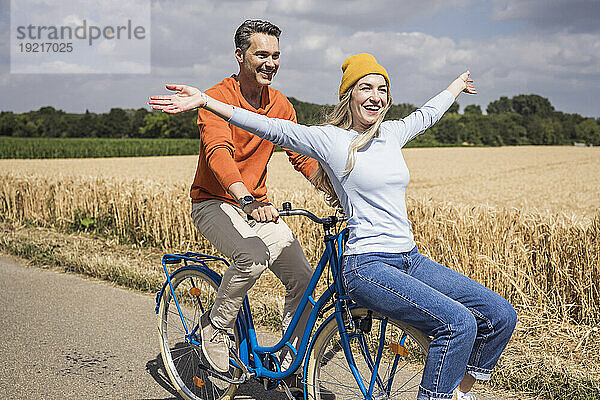 Fröhliche Frau genießt die Radtour mit Mann an einem sonnigen Tag