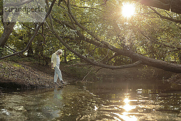 Reife Frau am Flussufer im Wald