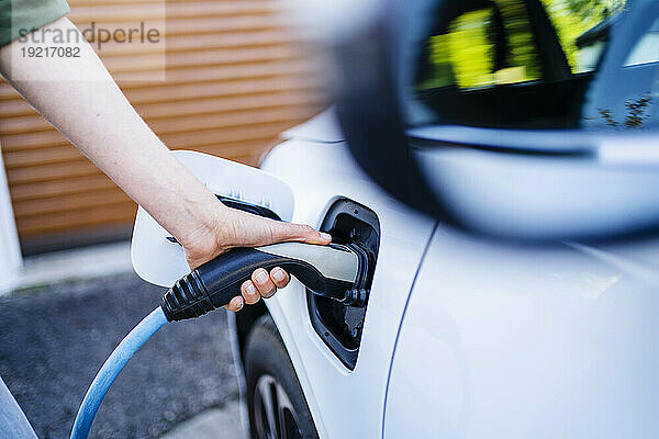 Hand einer Frau  die Elektroauto auflädt