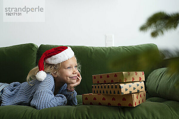 Smiling girl lying near Christmas presents at home