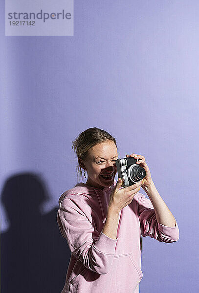 Lächelnde Frau fotografiert mit der Kamera im Studio