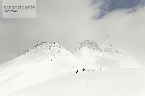 Männer wandern auf schneebedecktem Berg unter Himmel