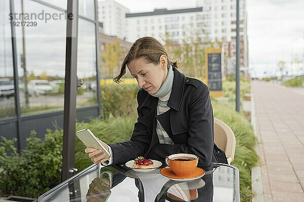 Frau benutzt Smartphone im Straßencafé