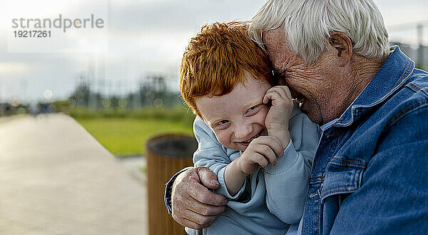 Glücklicher Großvater umarmt Enkel im Park