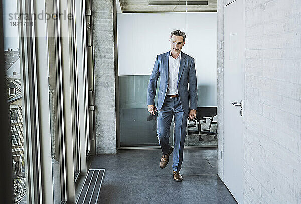 Mature businessman walking in office corridor