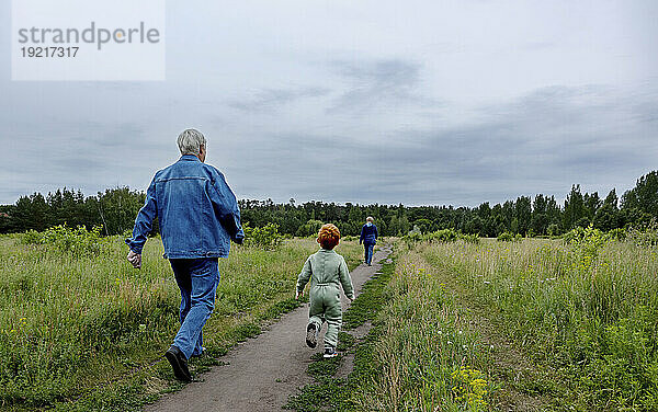 Großeltern und Enkel gehen auf Fußweg im Park