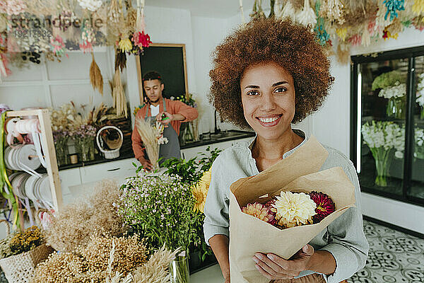 Lächelnder Kunde hält Blumenstrauß im Geschäft