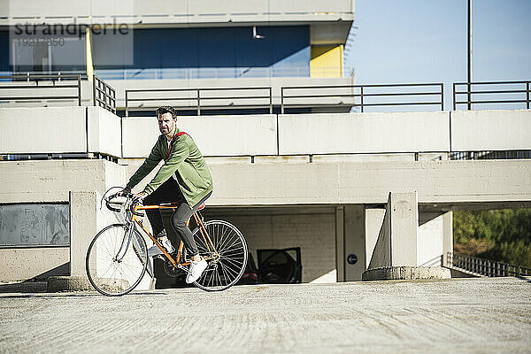 Mann fährt an sonnigem Tag Fahrrad in der Nähe von Gebäude
