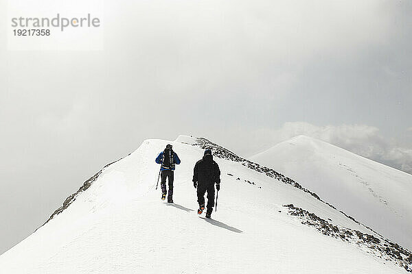 Männer wandern mit Stock auf schneebedecktem Berg