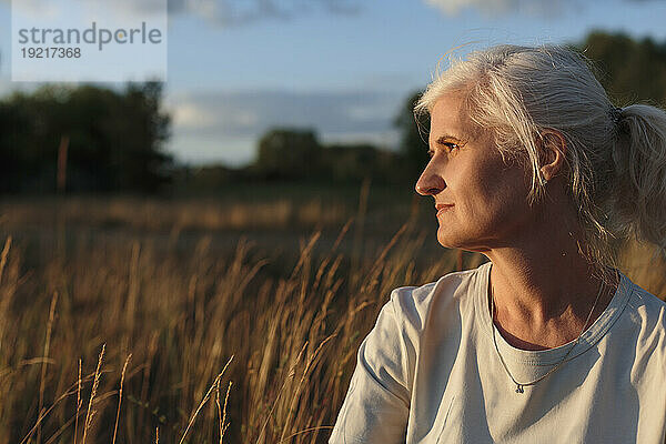 Reife Frau mit grauen Haaren bei Sonnenuntergang