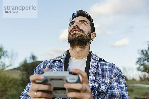 Mann schaut nach oben und hält Drohnen-Controller in der Hand