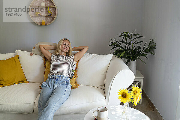 Mature woman relaxing on sofa in living room at home