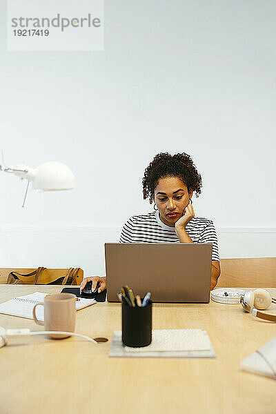 Junge Studentin lernt am Laptop am Schreibtisch