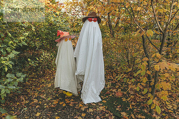 Mädchen in Halloween-Kostümen stehen inmitten von Pflanzen im Garten