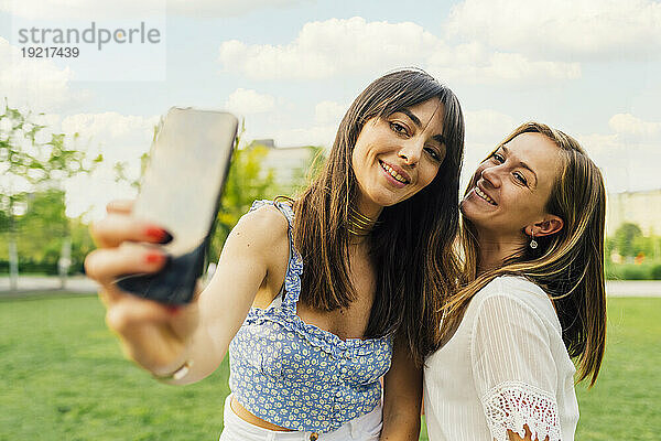 Glückliche Frau macht Selfie mit Freund im Park