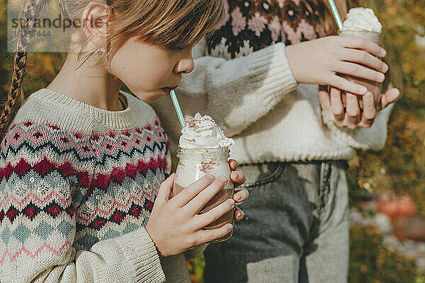 Mädchen trinken Milchshake im Garten